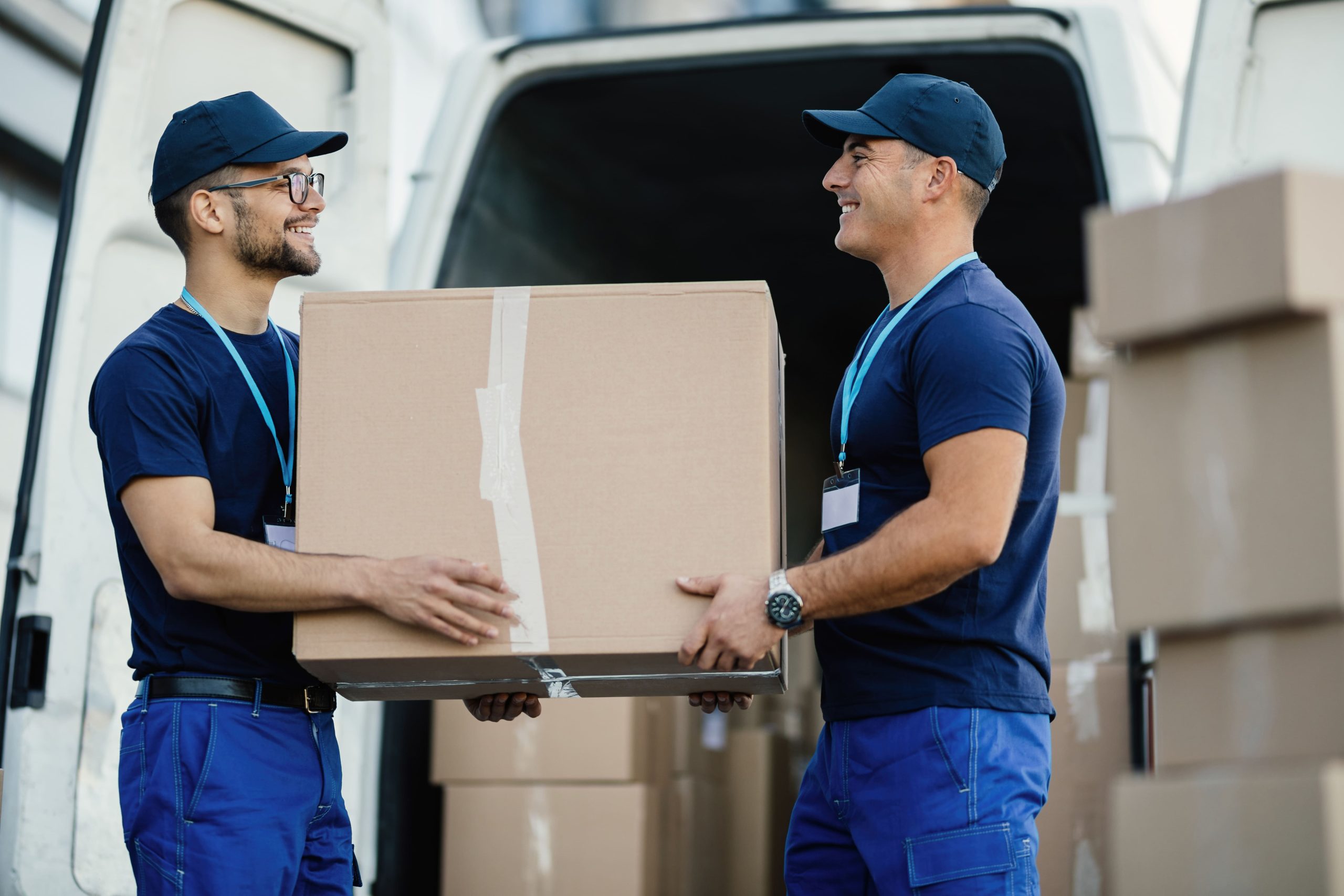 happy-manual-worker-cooperating-while-carrying-cardboard-boxes-delivery-van